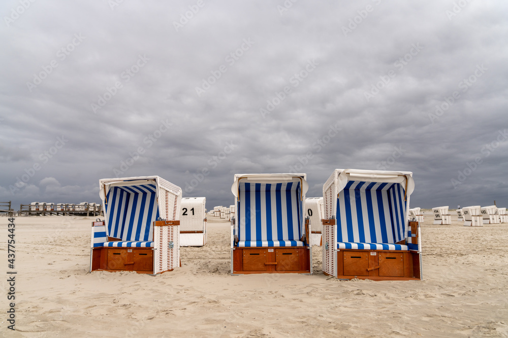 colorful beach baskets on an idyllic golden sand beach on the German Wadden Sea coast under an expressive sky colorful beach baskets on an idyllic golden sand beach on the German Wadden Sea coast under an expressive sky