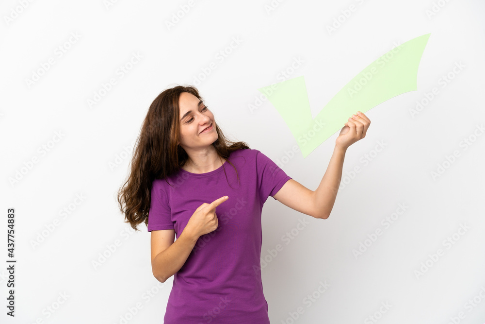 Young caucasian woman isolated on white background holding a check icon and pointing it Young caucasian woman isolated on white background holding a check icon and pointing it