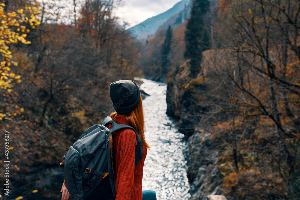 woman hiker with backpack near river mountains autumn forest travel