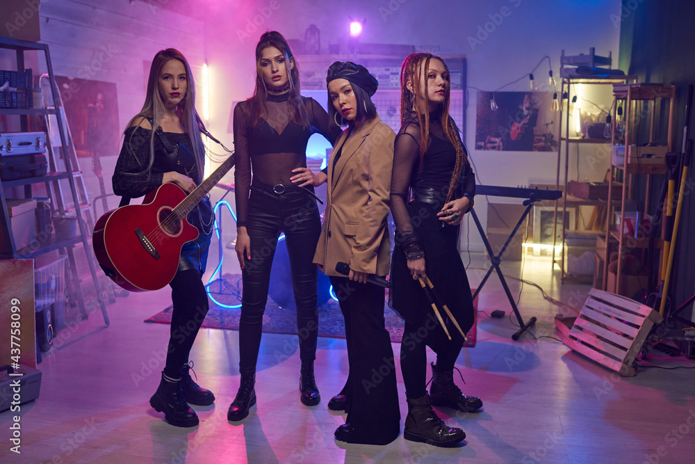 Fototapeta premium Group of young women with musical instruments standing in studio