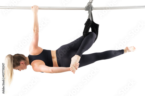 Fotografiet Woman doing pilates exercises in a cadillac equipment, white  backgound, high key