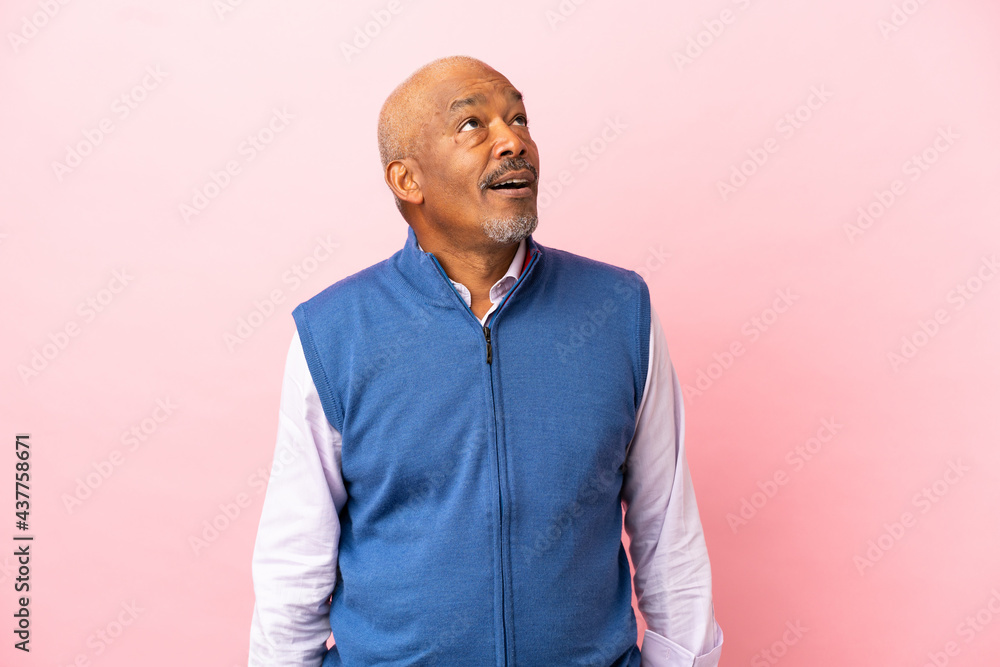 Cuban senior isolated on pink background looking up and with surprised expression Cuban senior isolated on pink background looking up and with surprised expression