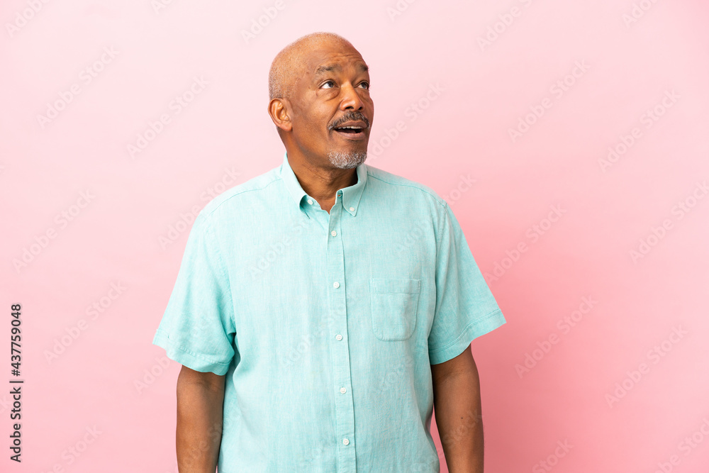 Cuban senior isolated on pink background looking up and with surprised expression Cuban senior isolated on pink background looking up and with surprised expression