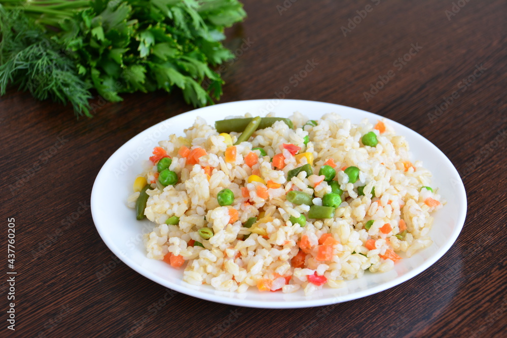 brown rice with vegetables and salad greens on the wooden kitchen table brown rice with vegetables and salad greens on the wooden kitchen table