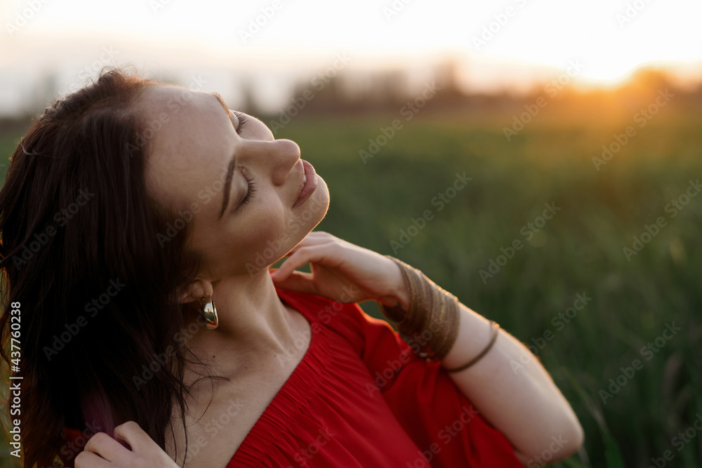 beautiful hispanic young woman in red dress dancing in a field at sunset
