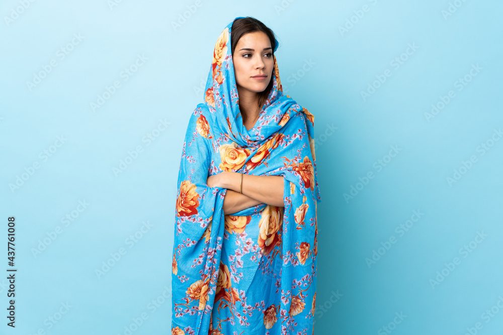 Young Moroccan woman with traditional costume isolated on blue background looking to the side