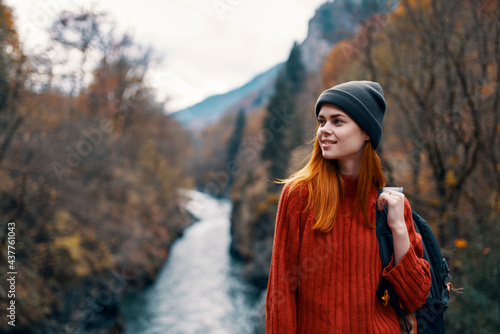 woman hiker in autumn forest near river mountains travel