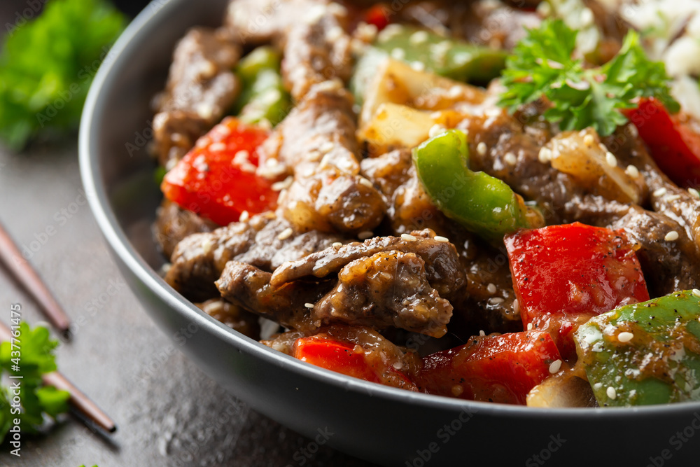 Stir fry Chinese pepper beef steak with onion, red and green bell pepper, rice in bowl Stir fry Chinese pepper beef steak with onion, red and green bell pepper, rice in bowl