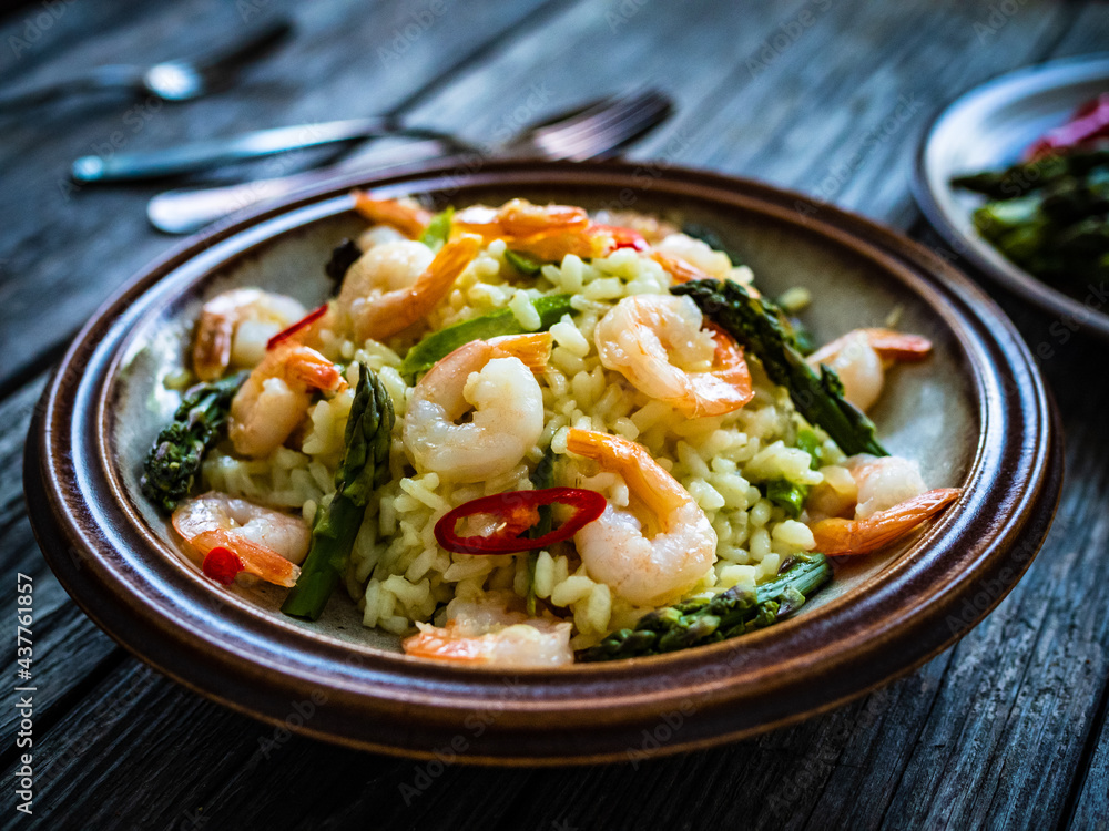 Risotto with prawns and asparagus on wooden background
Risotto with prawns and asparagus on wooden background