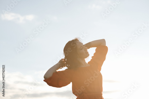 Fototapeta Naklejka Na Ścianę i Meble -  beautiful hispanic young woman in red dress dancing in a field at sunset