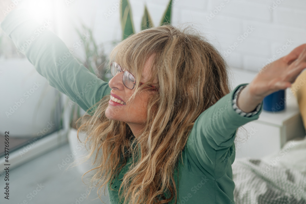 Fototapeta premium middle-aged adult woman waking up in the morning in the bedroom happy with energy