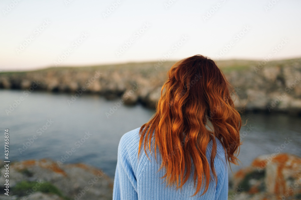 red-haired woman in sweater outdoors rocky mountains vacation