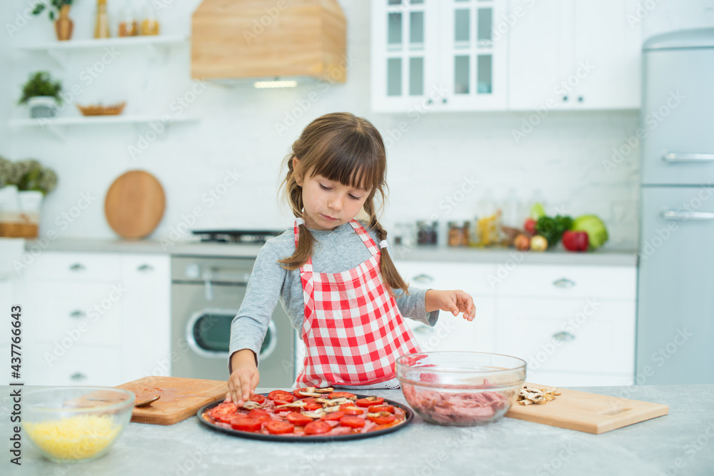 Funny girl with pigtails prepares pizza in the kitchen. Cooking class for children Funny girl with pigtails prepares pizza in the kitchen. Cooking class for children