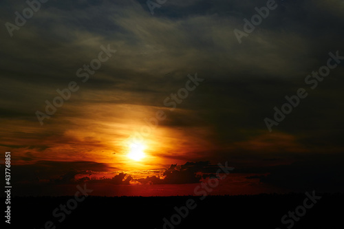 beautiful sunset sky  bright sun and dark silhouette of clouds as a background