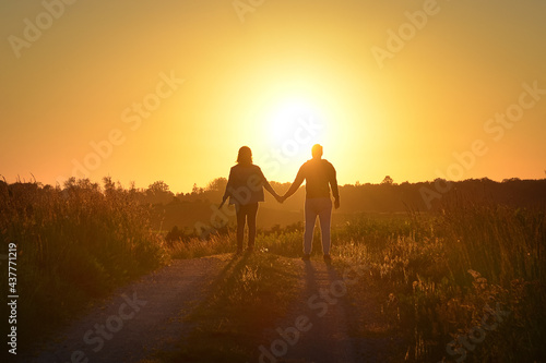 Fototapeta Naklejka Na Ścianę i Meble -  Young couple holding hands towards the Sun