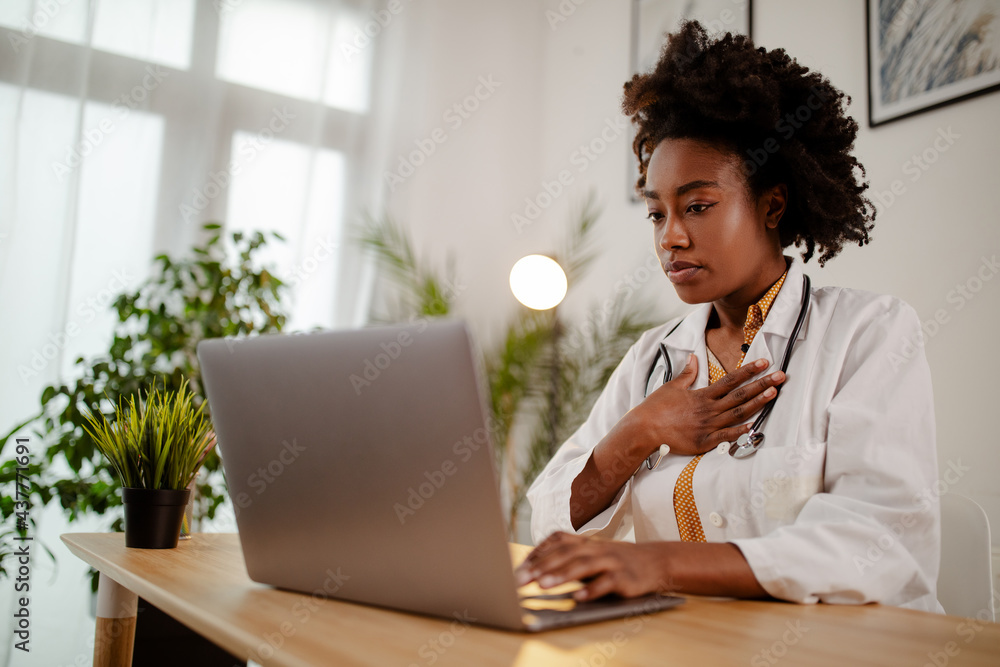 Female Afro American doctor having video conference on laptop with colleagues. Female Afro American doctor having video conference on laptop with colleagues.