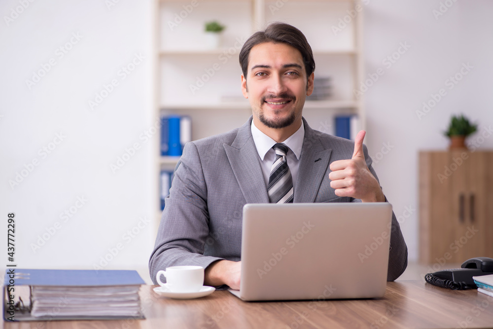 Young attractive male employee sitting at workplace Young attractive male employee sitting at workplace