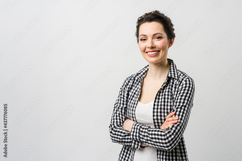 Business portrait of a young woman. A charming brunette looks at the camera, crossing her arms over her chest. Business portrait of a young woman. A charming brunette looks at the camera, crossing her arms over her chest.