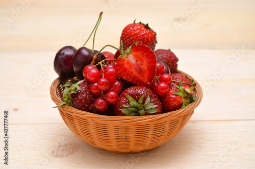 different summer berries in a basket strawberries, cherries and red currants