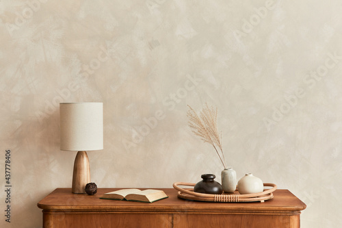 Minimalist composition of living room with wooden commode, table lamp, dried flower in vase, book, decoration and elegant personal accessories in stylish home decor. Template. Copy space.