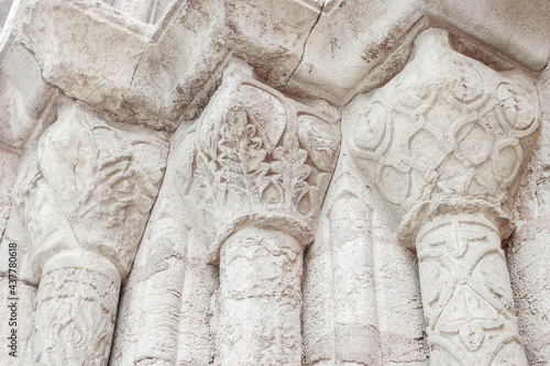 Closeup of stone columns, pilars of a medieval gothic church building in Coimbra town, Porugal, Europe. Architectural detail, beautiful sandstone facade with floral decor. photo