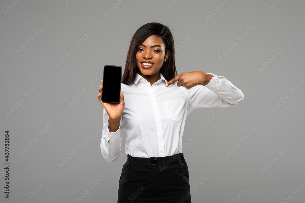 Young african business woman pointed on phone screen isolated on gray background Young african business woman pointed on phone screen isolated on gray background
