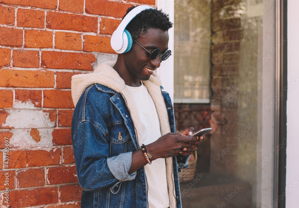 Portrait of young african man with smartphone listening to music on city street