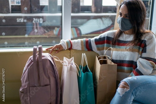 たくさんの買い物袋を持って待合室で待つ南米の女性