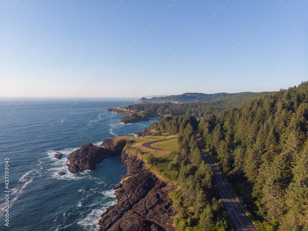 In the photo we see a highway near the ocean. Mountainous terrain. Lots of greenery. Blue cloudless sky. Beautiful landscape. Place for your insert.