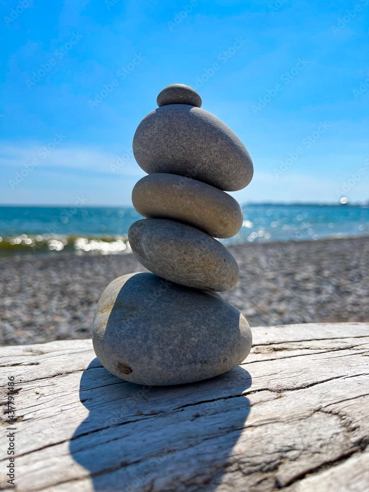 Fototapeta premium Cairn of Beach Pebbles on Driftwood