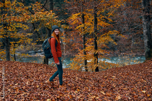a traveler with a backpack walks in the park in nature near the river in autumn