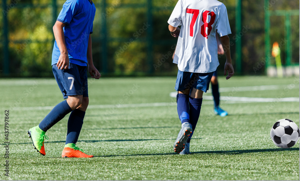 Young sport boys in blue sportswear running and kicking a ball on pitch. Soccer youth team plays football in summer. Activities for kids, training Young sport boys in blue sportswear running and kicking a ball on pitch. Soccer youth team plays football in summer. Activities for kids, training