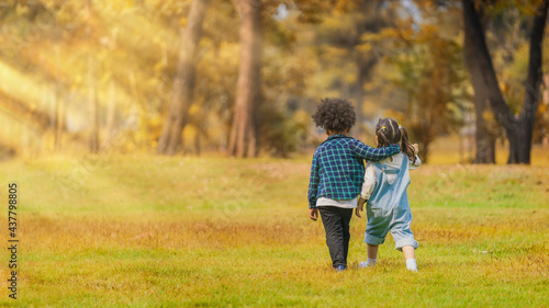two diverse mixed race children boy and girl play together in park during autumn