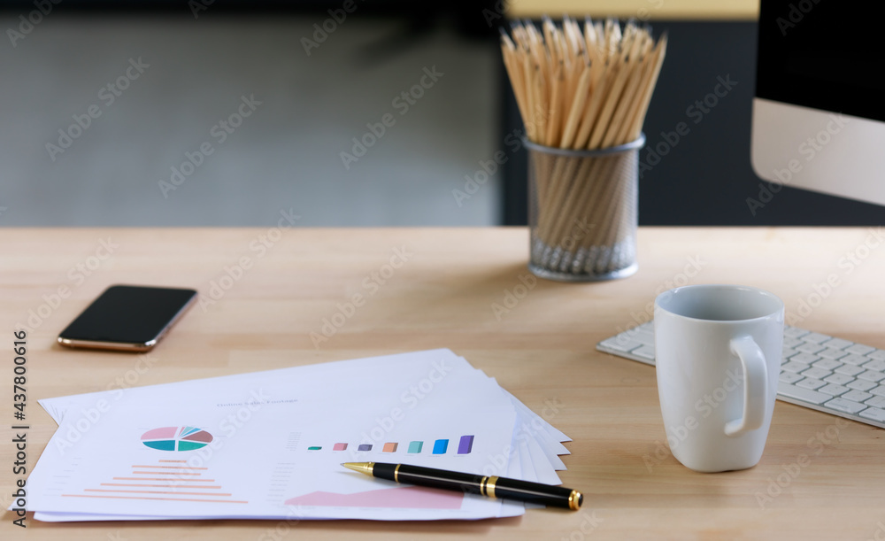 Morning paper work with coffee mug and pile of pencils and iphone on wooden table in office with natural lighting Morning paper work with coffee mug and pile of pencils and iphone on wooden table in office with natural lighting