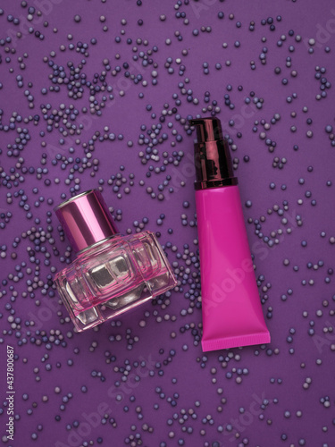 Cosmetic cream and perfume on a background of purple balloons.