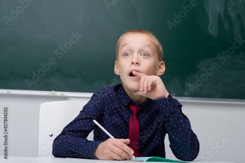 Thinking schoolboy studying at school photo