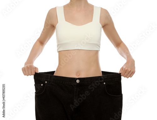 Young woman wearing big jeans after weight loss on white background, closeup