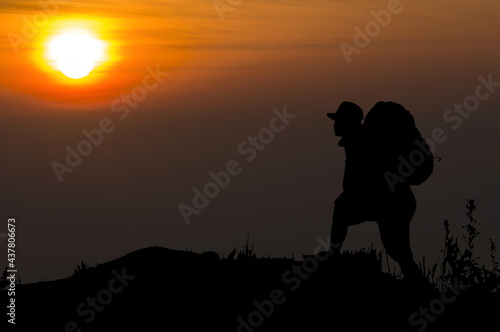 Travel young asian man tourist alone on the edge cliff mountains and looking on the valley. Silhouette of the person on the high rock at sunset. Hiking adventure lifestyle extreme vacations.
