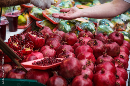 Outstretched hands selling ripe pomegranates 