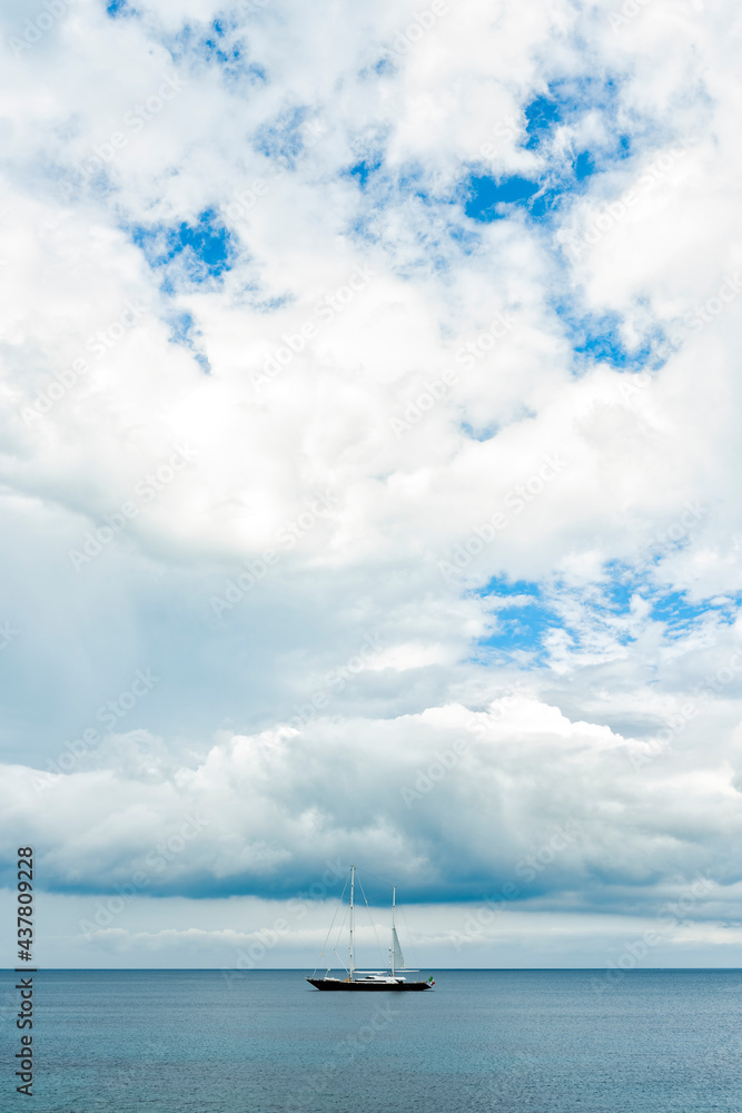 Fototapeta premium Stunning view of a luxury sailboat sailing on a beautiful calm sea during a dramatic, cloudy day.Sardinia, Italy. Recreational pursuit, copy space.