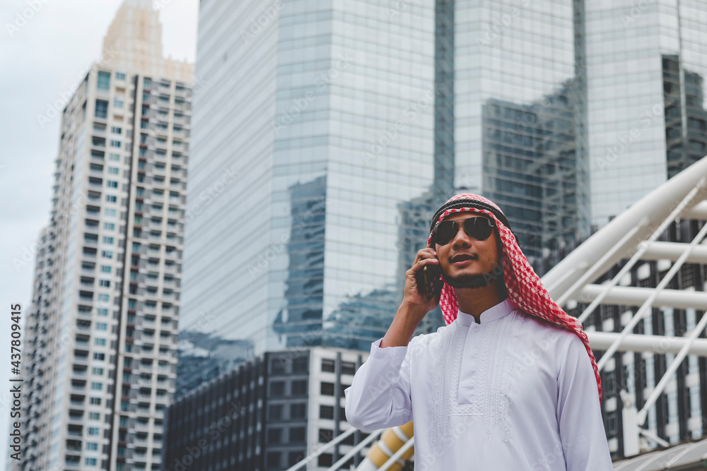 Fototapeta premium Islamic man using smartphones app organize schedule agenda focus on hands holding smartphone muslim modern uae city. Arab men wear hijab and muslim formal dress sending text sms online lifestyle