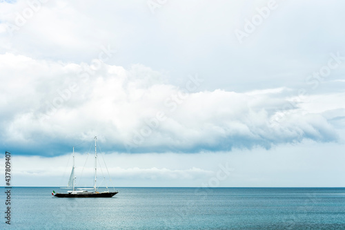 Stunning view of a luxury sailboat sailing on a beautiful calm sea during a dramatic, cloudy day. Costa Smeralda, Sardinia, Italy. Recreational pursuit, copy space.