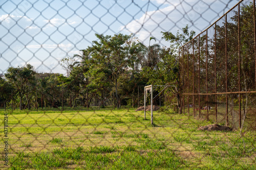 Campo de futebol mal conservado, grama alta e plantas envolvendo as traves. Efeito das restrições que proibiram os esportes amadores. photo