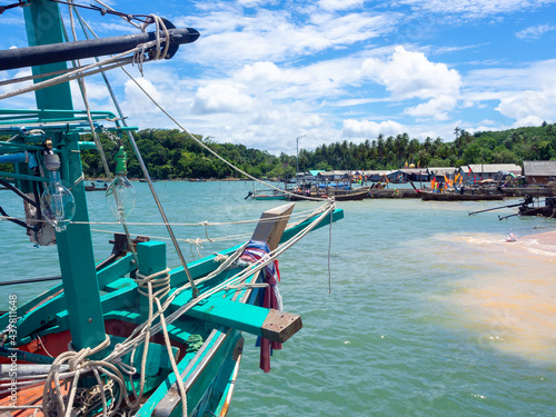 View of wooden local fisherman boat with light lamps and many messy ropes at the dock of fisherman village on seascape background in Thailand.