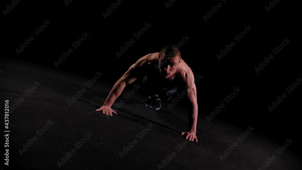 Young pumped man doing push ups in the dark arena Young pumped man doing push ups in the dark arena