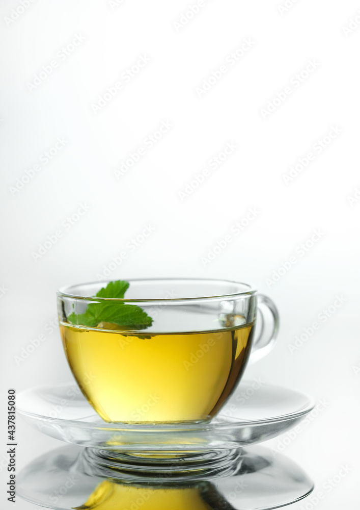 Yellow herbal tea in glass cup with leaf. Close-up  cup of freshly brewed hot tea.