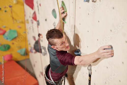 Young disabled man making effort while climbing wall