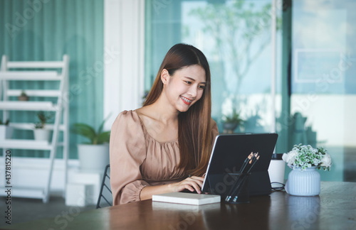 Business woman reading information on paperwork and using laptop working on desk.	