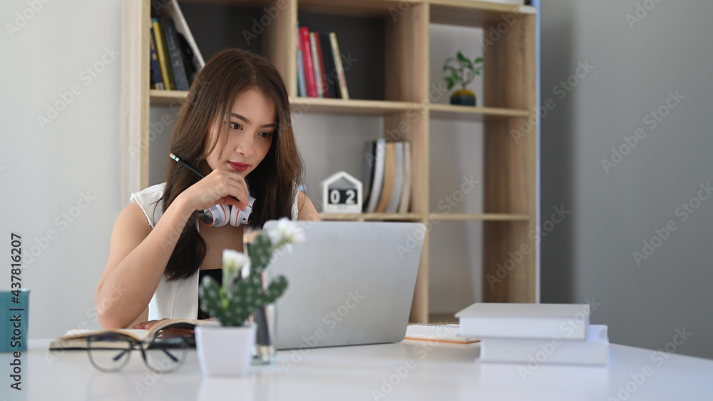Confident businesswoman watching webinar on laptop computer while sitting in modern office. Confident businesswoman watching webinar on laptop computer while sitting in modern office.