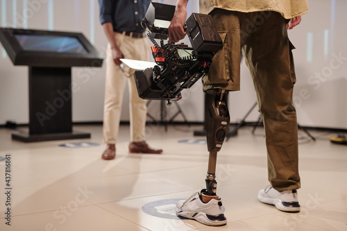 Cameraman with robotic leg standing in front of African guy in studio